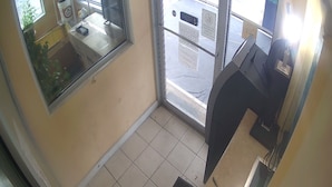 A small, enclosed area with a tiled floor, a window, and a counter with a cash register. - ECONOMY INN (Belleville)