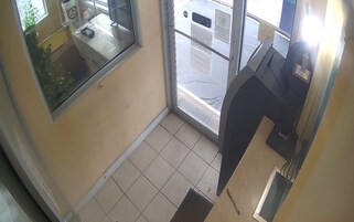 A small, enclosed area with a tiled floor, a window, and a counter with a cash register.