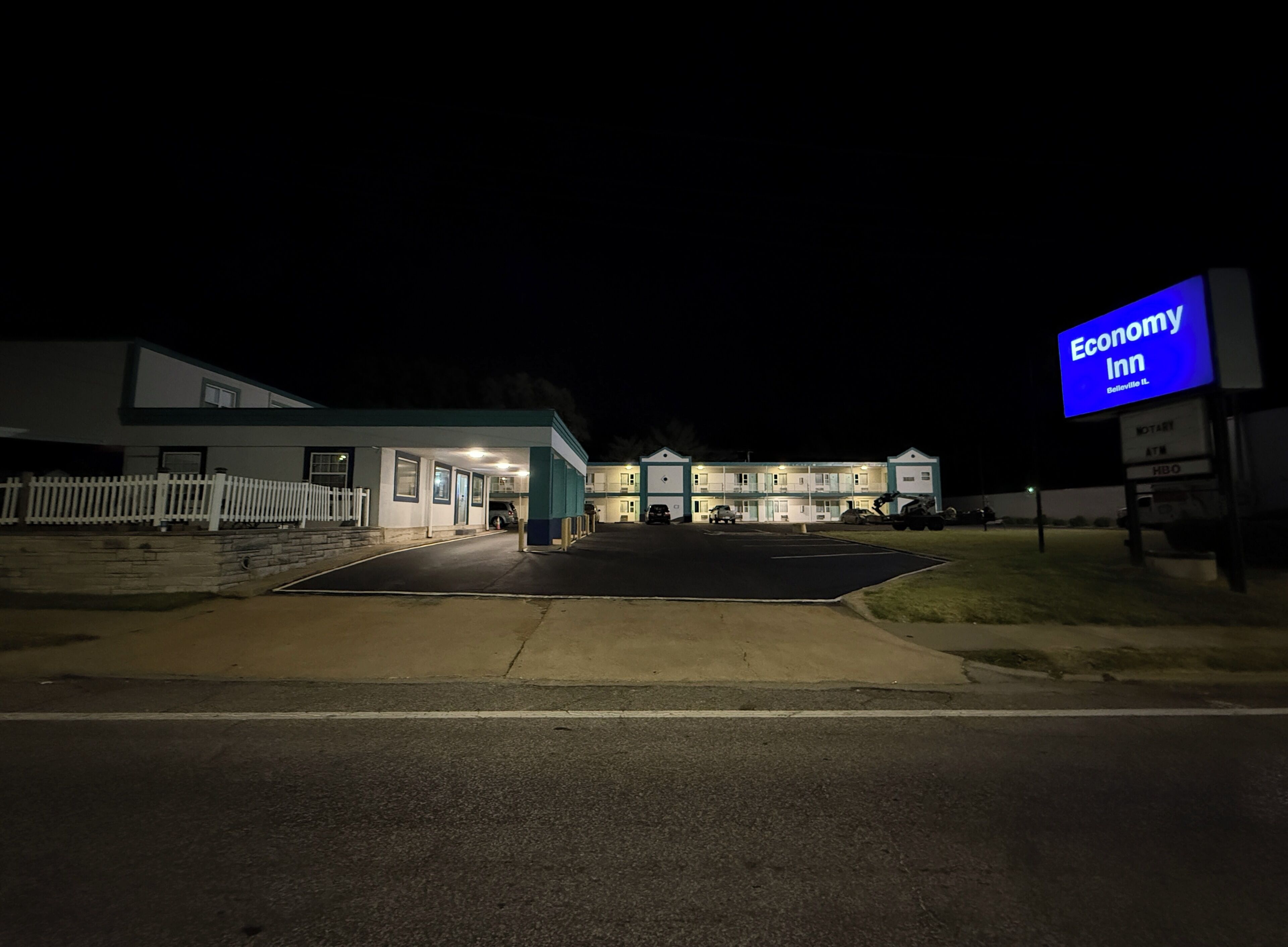 A motel with a signboard, a parking lot, and a building with multiple windows.