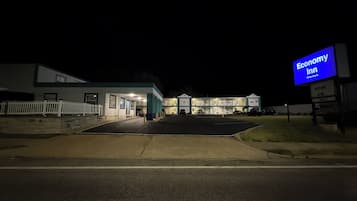 A motel with a signboard, a parking lot, and a building with multiple windows.