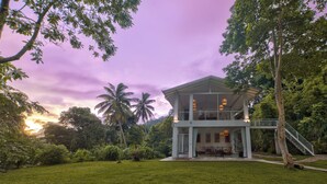 A two-story house with a balcony, surrounded by lush greenery and palm trees. - Colonial-style bungalow with private pool, mountain views  and tranquil vibes. (Kandy)