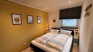 A bedroom with a bed, bedside lamps, a window with a view, and wall-mounted artwork. - Vacation apartment Kink in Wiesweg, only 5 min to Rapunzel Welt, perfect for couples (Legau)