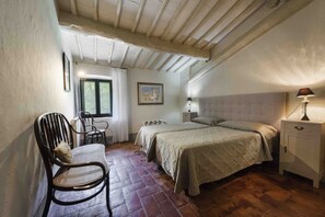 A bedroom with a double bed, a chair, a nightstand, and a window.