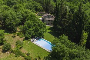 A house surrounded by dense forest with a swimming pool.