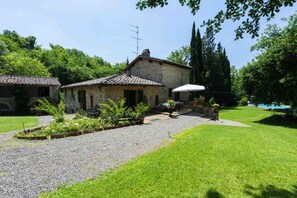A stone building with a tiled roof, a gravel pathway, and a grassy lawn.
