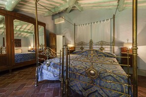 Une chambre à coucher avec un lit à baldaquin, un grand miroir et une armoire en bois.