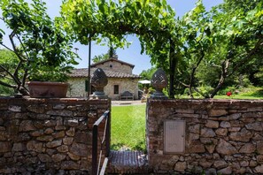 A stone wall with a gate leading to a stone building with a tiled roof.