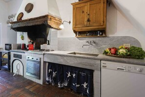 A kitchen with a wooden cabinet, a sink, a stove, a dishwasher, and a decorative curtain.