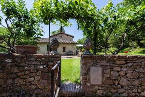 A stone wall with a gate leading to a stone building with a tiled roof.