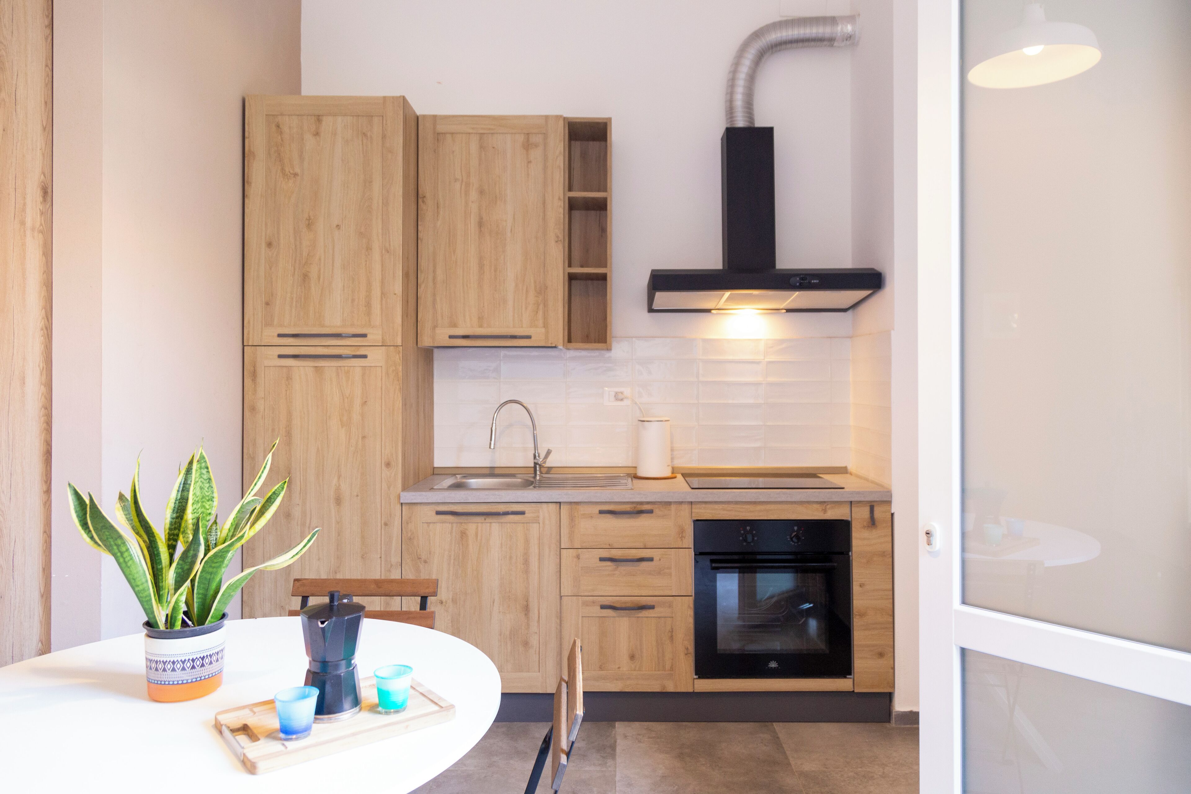 Een koelkast, een oven, een kookplaat, kookgerei, borden en bestek