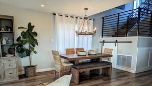 A dining area with a wooden table, wicker chairs, and a chandelier. - Walkable Ocean-View Lantern District Home with AC & Garage (Dana Point)