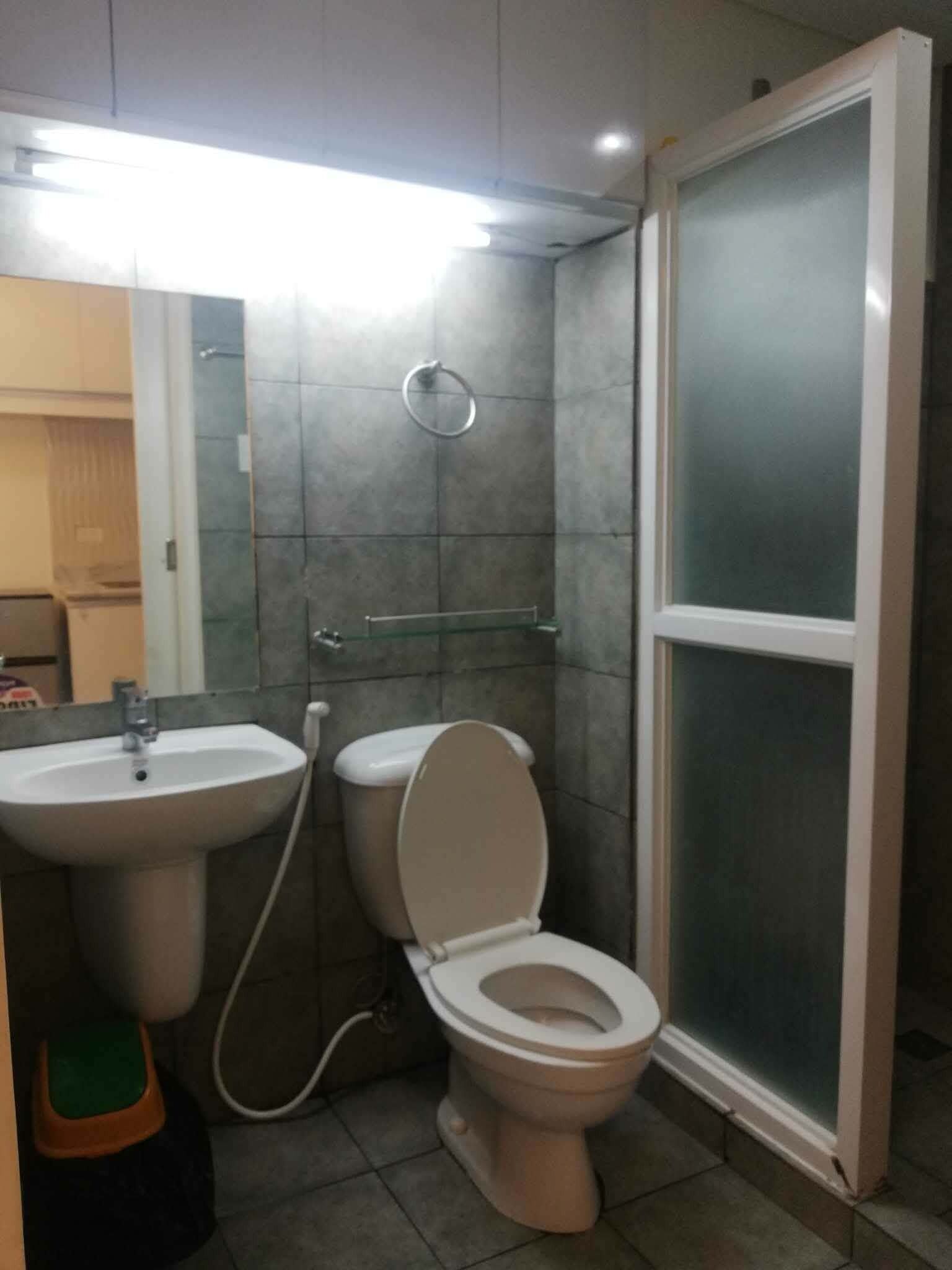 Et badeværelse med toilet, håndvask og brusebad.