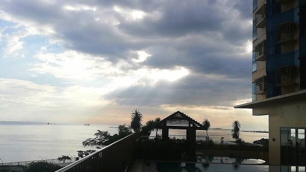 A coastal view with a building, a pool, and a beach. - Grand Riviera Condotel Near St Lukes Medical Center (Manila)