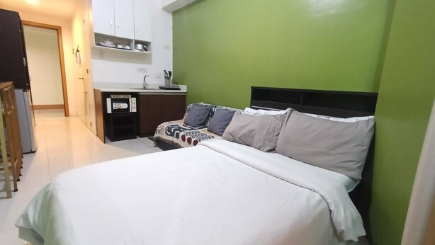 A bedroom with a bed, a bedside table, a mirror, and a green wall. - Grand Riviera Condotel Infront of us Embassy 17fl (Manila)