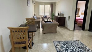 A modern living room with a dining area, a sofa set, a coffee table, and a small plant. - Royal Residence Cairo (Giza)