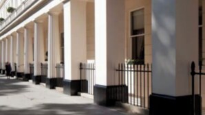 A row of classical-style buildings with columns and decorative moldings.