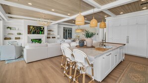 Una cocina amplia con una isla grande, armarios blancos y techo de madera.