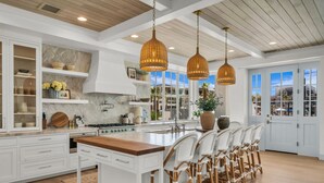 Una cocina amplia con una isla grande, armarios blancos y vistas al exterior.