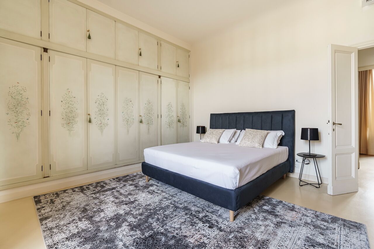 A bedroom with a bed, a wardrobe, and a bedside table.