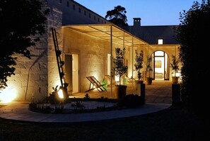 A modern building with a glass facade, outdoor seating area, and potted plants.