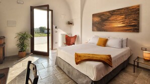 Un dormitorio con una cama grande, una planta en maceta, una silla y un cuadro en la pared.