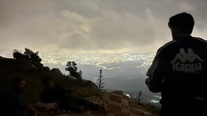 Una persona damunt d'un turó contemplant una ciutat de nit.