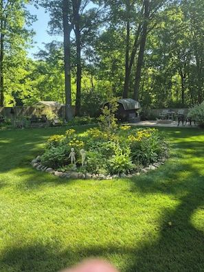A well-maintained garden with a central flower bed, a wooden fence, and a seating area with chairs and a table. - Ideal for traveling professionals. Private 2-bedroom home in peaceful Mansfield. (Mansfield)