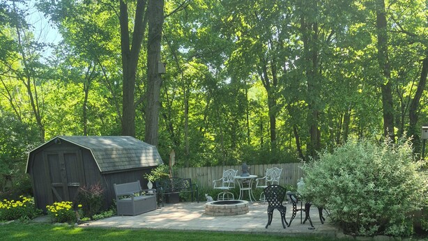 A backyard with a wooden shed, a barbecue area, and a seating arrangement.