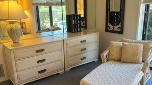 A bedroom with a bed, dresser, and two mirrors.