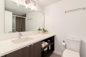 Ein modernes Badezimmer mit einem großen Spiegel, einem Waschbecken, einer Toilette und einer Dusche.