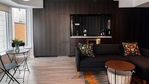 A modern living room with a dark sofa, a round coffee table, and a dining area with a small table and chairs.