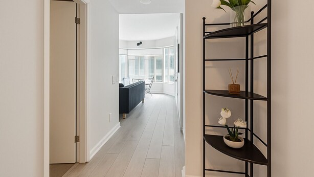 A hallway with a black metal shelf holding decorative items and a vase of white flowers.