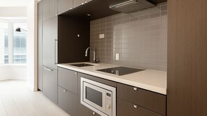 A modern kitchen with dark cabinetry, a double sink, and a built-in oven.