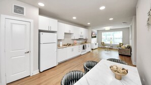 Une cuisine moderne avec des meubles blancs, un four encastré et un coin repas comprenant une table et des chaises en marbre.