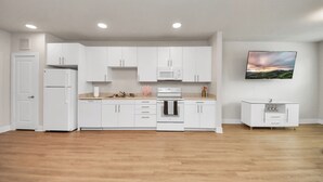 Une cuisine moderne avec des meubles blancs, un four à micro-ondes, un four et un petit meuble blanc.