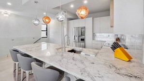 A modern kitchen with a marble countertop, stainless steel appliances, and pendant lighting. - Stylish Oceanview Kayak Getaway w/ Pool & Hot Tub! (Key Largo)