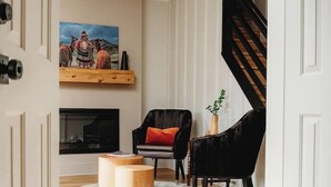 Una sala de estar moderna con chimenea, una silla negra, una mesa de centro de madera y una escalera.