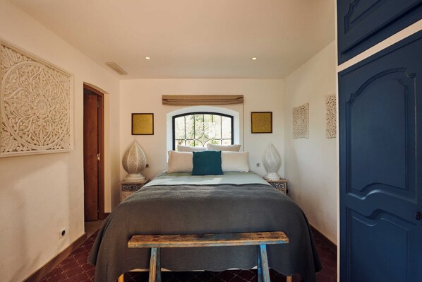 Quarto com cama, janela, porta e decoração na parede.