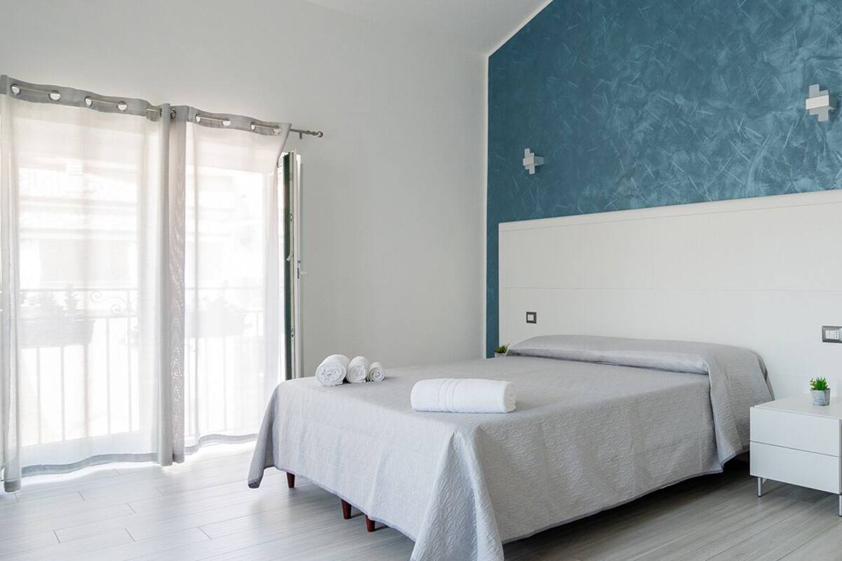 A modern bedroom with a bed, a nightstand, and a wardrobe.