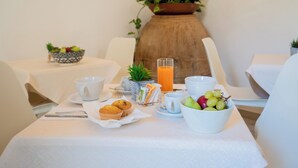 A breakfast setup with a bowl of fruit, muffins, a glass of orange juice, and a cup on a table. - Harmonia home (Capitello)