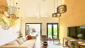 A modern living room with a sofa, a wooden coffee table, a TV, and a ceiling fan. - Vibey, spacious 3-bedroom villa with WiFi, AC, Pool, in the heart of Canggu (Canggu, Kec.Kuta Utara, Kab. Badung)