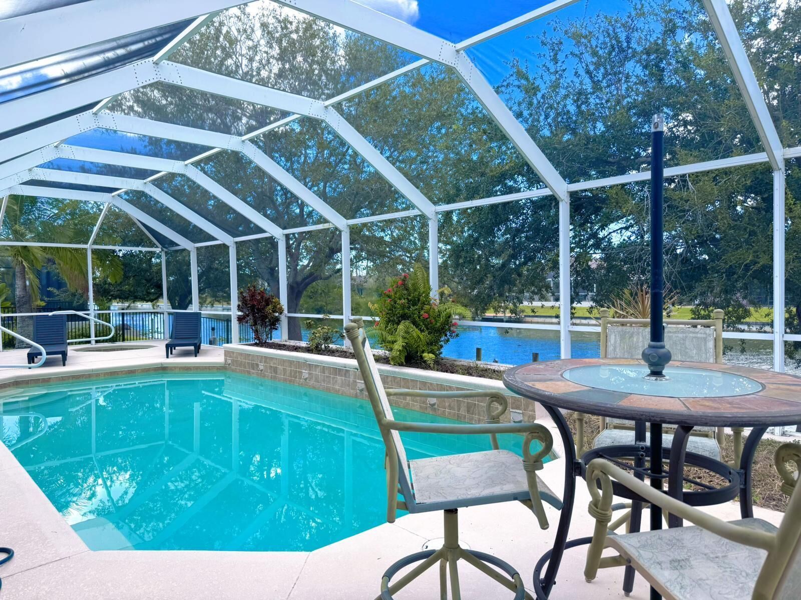 Un espace piscine extérieur abrité, offrant une vue dégagée sur la piscine, des chaises longues et une table avec des chaises.