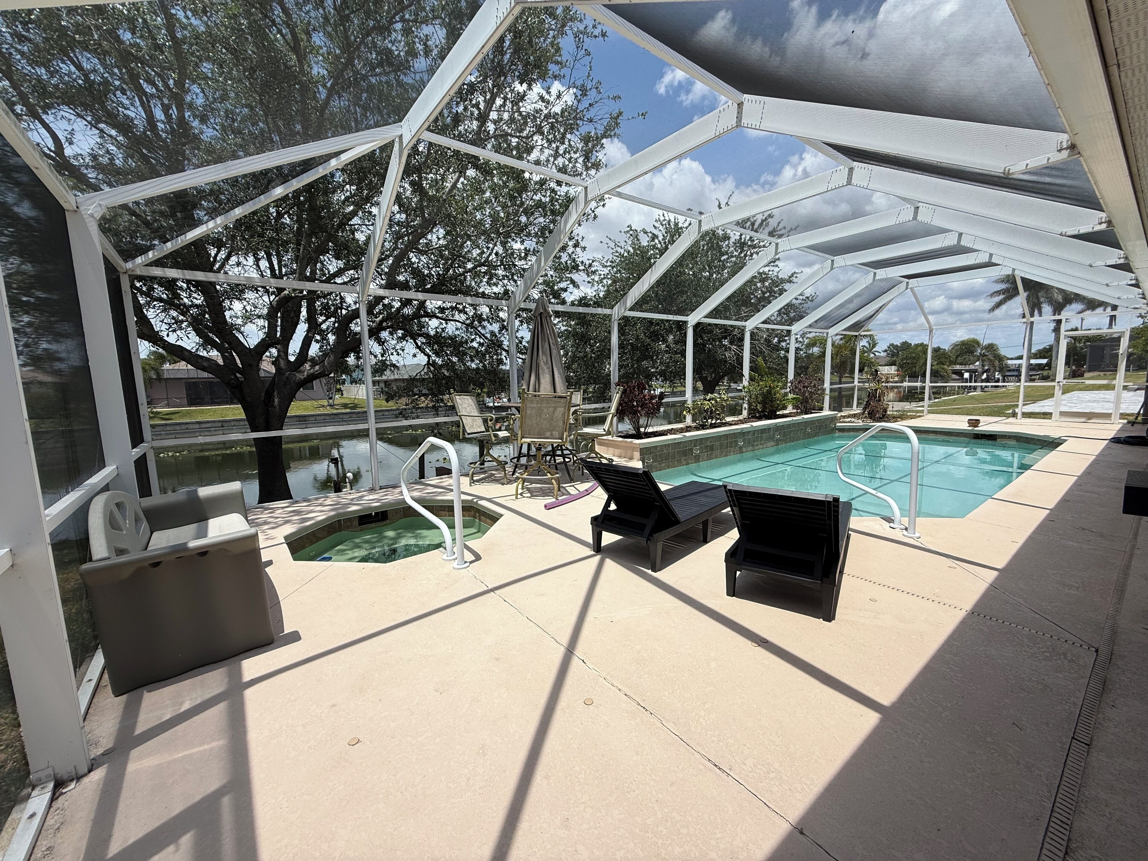 Zona de piscina exterior cubierta con sillones reclinables y una bañera de hidromasaje.