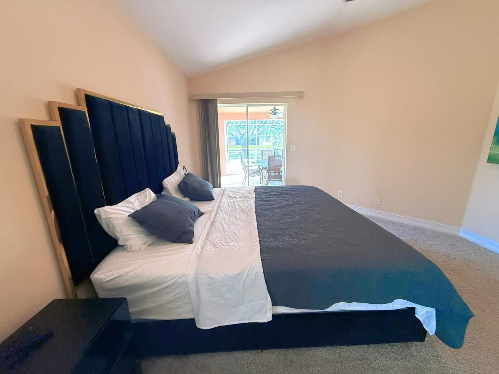 A bedroom with a large bed, a headboard, and a view of an outdoor area.