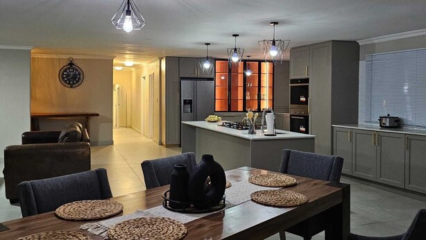 Een moderne keuken met een centraal eiland, inbouwapparatuur en hanglampen.