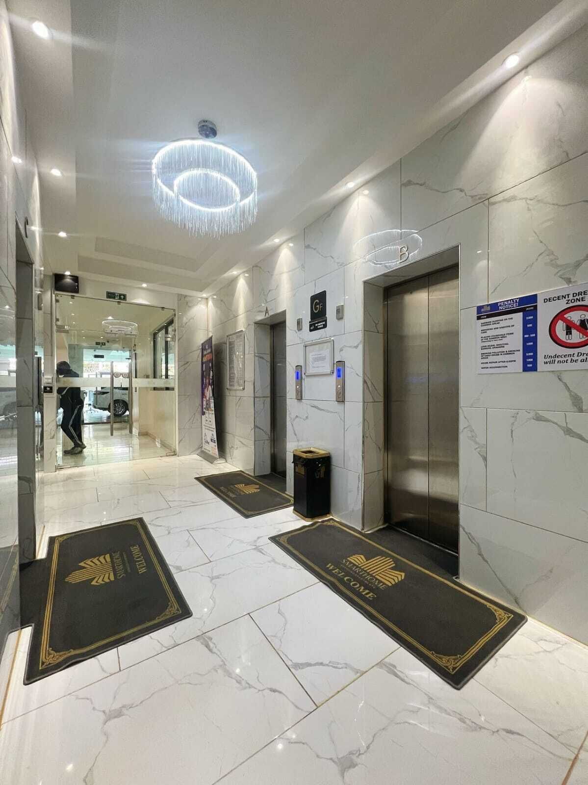 En hotellobby med marmorgolv, en kristallkrona, hissar och en välkomstmatta.