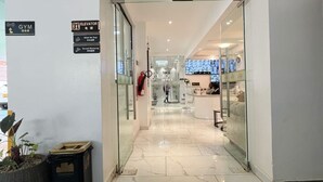 A hotel entrance with a reception desk, a gym sign, and an elevator sign. - Pazoori Stays at SmartHomes (Nairobi)