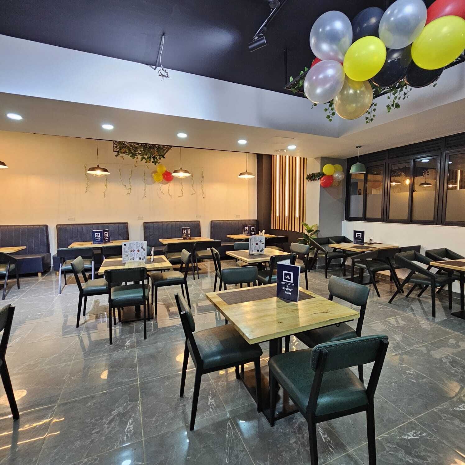Un interno ristorante moderno con banconi e tavoli, un cartello con il menù e palloncini decorativi.
