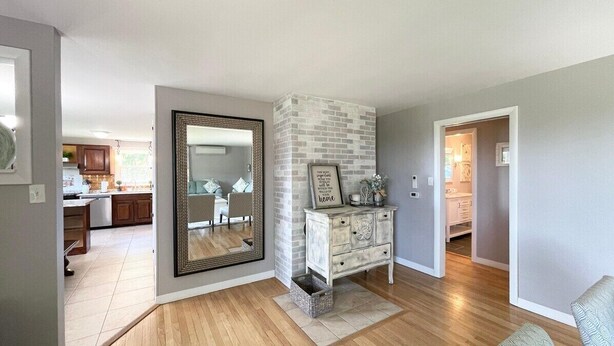 A modern living room with a large mirror, a white dresser, and a small rug.