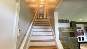 A staircase with wooden steps leading to a landing, a stone wall, and a television mounted on the wall.